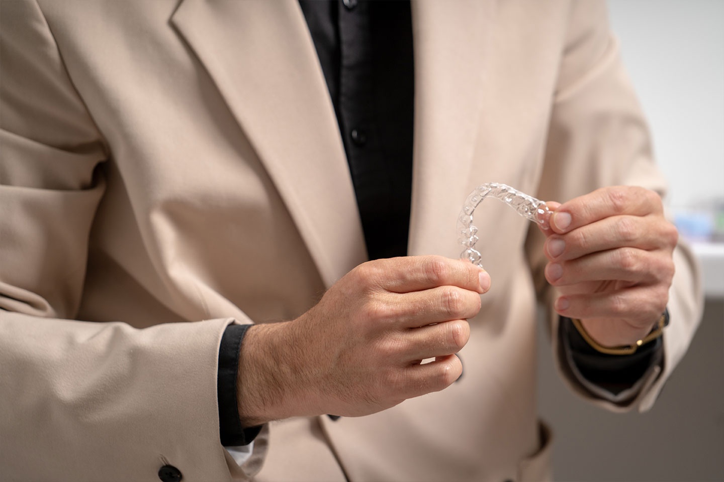 A man in a suit holding clear aligners