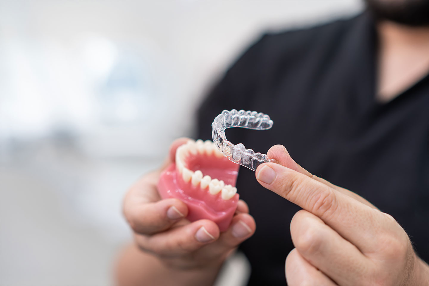 Dentist showcasing a clear aligner with a teeth model